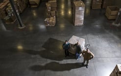 A group of three warehouse workers standing in the center of a distribution warehouse.