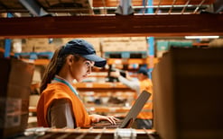 Female worker in a warehouse using a laptop for the multichannel fulfillment alternatives to Amazon blog