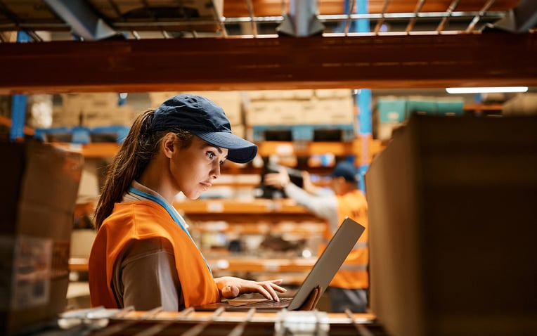 Female worker in a warehouse using a laptop for the multichannel fulfillment alternatives to Amazon blog