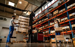 Below view of a group of workers cooperating in a warehouse for the dedicated warehousing solution optimization page.