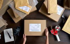 Top view of female warehouse worker packing shipping order box for the 3PL pricing model