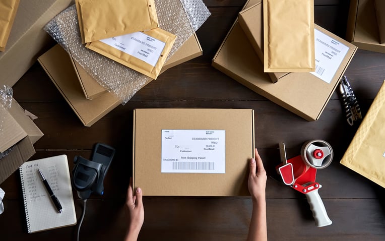 Top view of female warehouse worker packing shipping order box for the 3PL pricing model