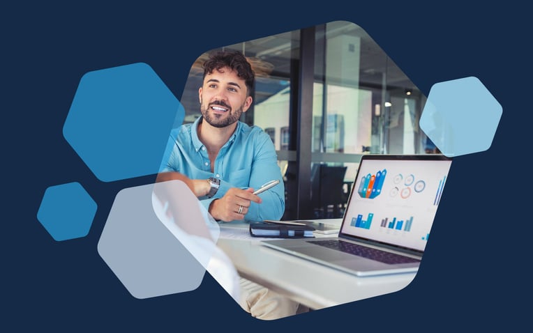 man with pen next to laptop with graphs and metrics